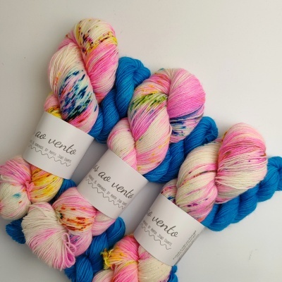 Três novelos de lã multicolorida com etiquetas brancas ao vento