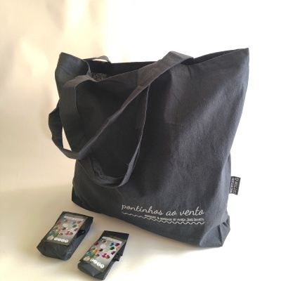 Saco de tecido preto com alças largas e dois pacotes pretos com etiquetas coloridas