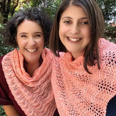 Duas mulheres usam cachecóis cor de rosa tricotados ao ar livre no outono
