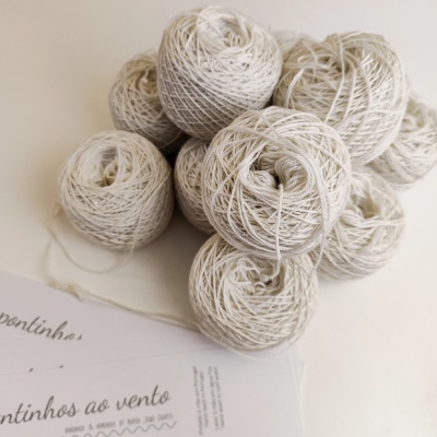 Novelos de fio branco sobre mesa com papel ao lado