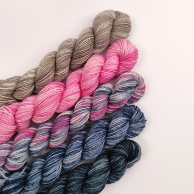 Novelos de lã em várias cores alinhados sobre fundo branco