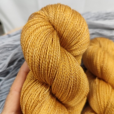 Novelo de lã amarelo-mostarda com textura fina e fios torcidos