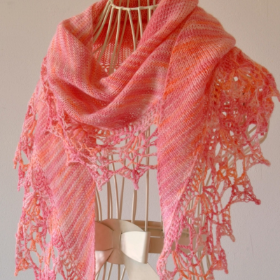 Lenço triangular rosa e laranja com borda calada numa estrutura metálica branca