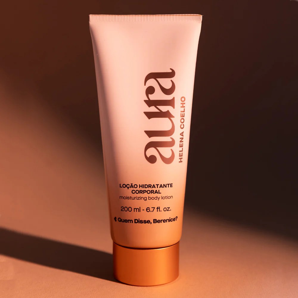 Tubo de loção hidratante corporal rosa com tampa laranja e texto em castanho, sobre fundo castanho.