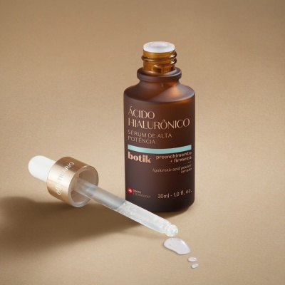 Frasco de sérum ácido hialurónico com conta-gotas e líquido em fundo bege.
