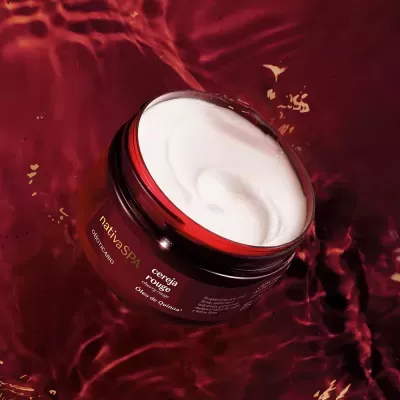 Pote de creme nativaSPA aberto com creme branco sobre fundo vermelho líquido