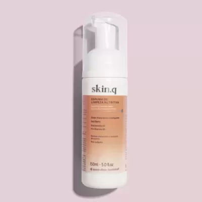 Frasco branco de espuma de limpeza da skin.q sobre superfície rosa