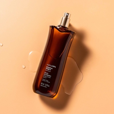 frasco de perfume ou óleo corporal castanho com tampa prateada em superfície bege