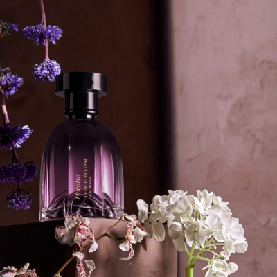 Frasco de perfume Roxette Super Eclipse com flores numa base escura