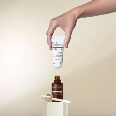 Frasco de vidro âmbar com soro e tubo branco de refil botik sobre fundo bege