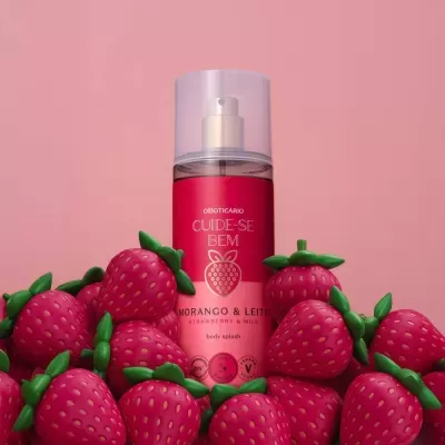 Frasco de body splash rosa com morangos artificiais à volta