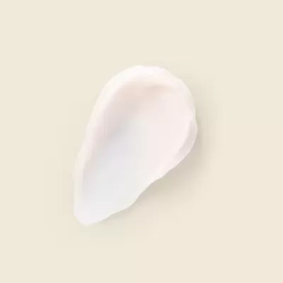 Amostra de creme branco com textura suave sobre fundo bege