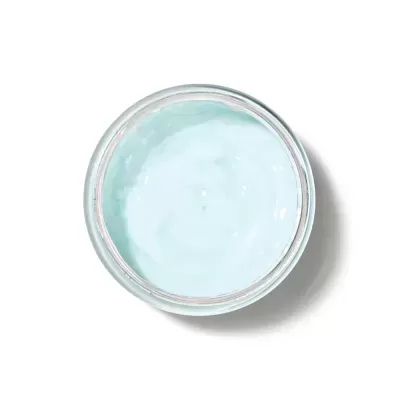 Frasco de vidro com creme azul claro visto de cima