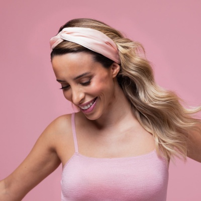 Mulher com faixa de cabelo rosa claro e top rosa claro com alças finas