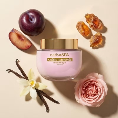 Frasco rosa de creme perfumado com ameixa e elementos naturais ao redor