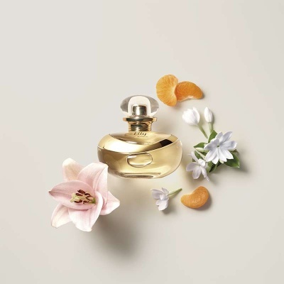 Frasco de perfume dourado com flores e tangerina