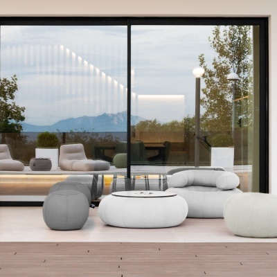 Conjunto de puffs e mesa oval em tecido cinza claro e cinza escuro em espaço exterior com janela de vidro ao fundo