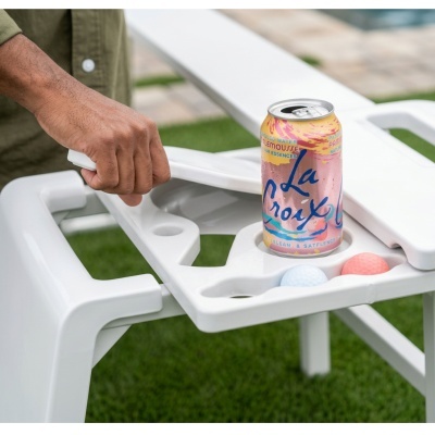Lata La Croix rosa e amarelo em cadeira de plástico branca com bolas de golfe, ao ar livre