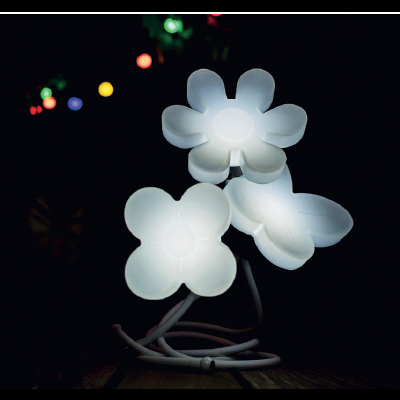 Candeeiro com flores brancas iluminadas em fundo escuro com luzes coloridas