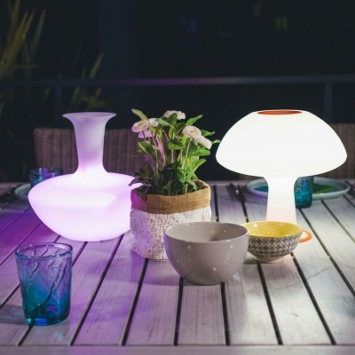 Mesa de madeira com vasos luminosos, plantas e tigelas coloridas