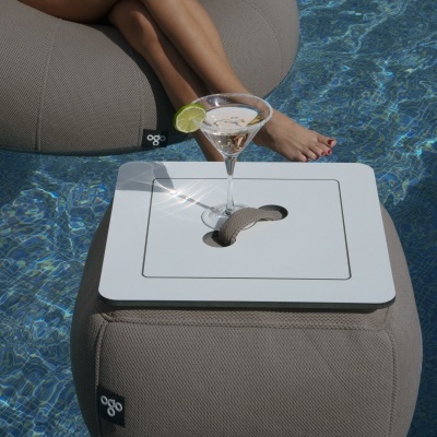 Puff cinza e bandeja branca com copo de cocktail numa piscina