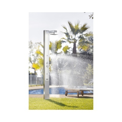Ducha exterior em aço inoxidável com água a cair junto a piscina e relva.