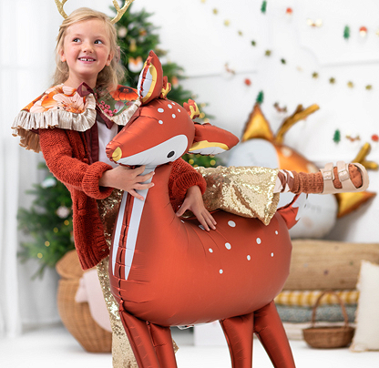 Criança segurando balão de veado em ambiente decorado para Natal