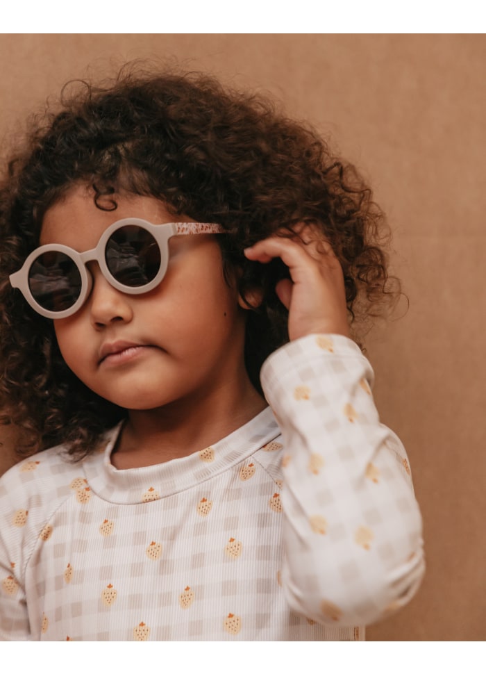 Criança com óculos de sol redondos e camisola com padrão xadrez e cones de gelado