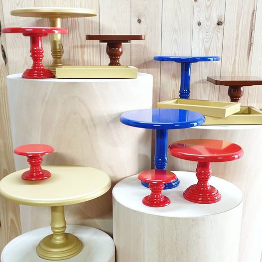 Suportes de bolos coloridos em diferentes tamanhos sobre cilindros de madeira.