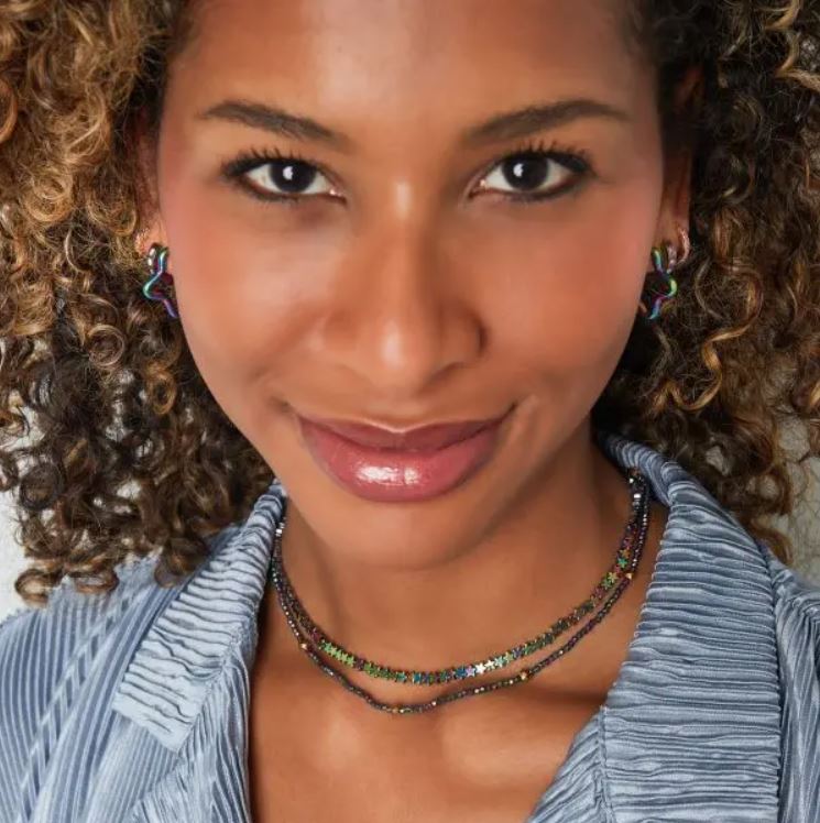 Mulher com brincos e colares coloridos usando camisa azul texturizada