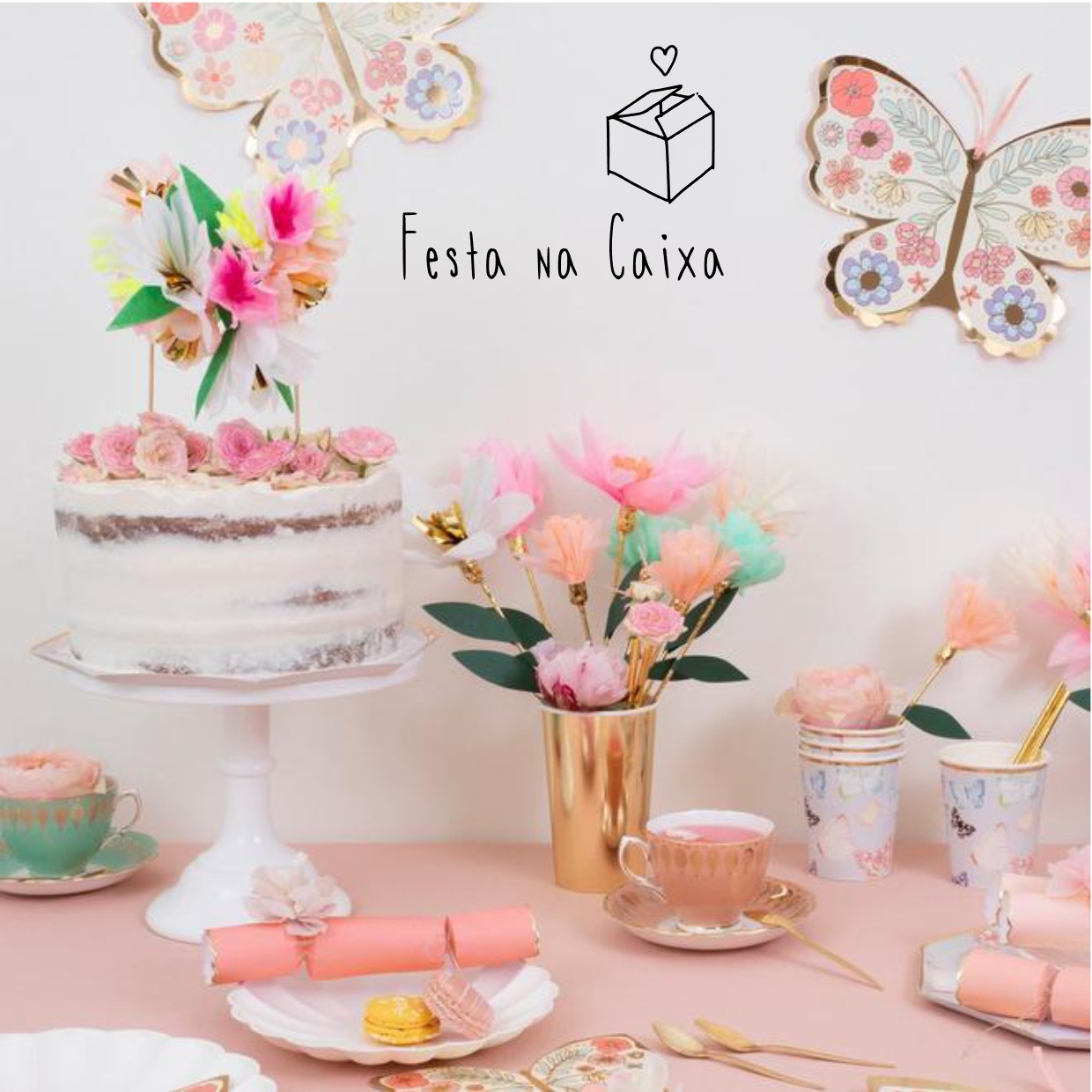 Mesa com bolo decorado, chávenas pastel, flores de papel e borboletas decorativas na parede