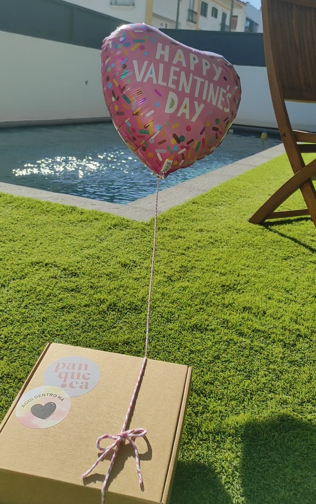 Balão em forma de coração rosa com texto 'HAPPY VALENTINES DAY' e caixa de cartão com etiqueta
