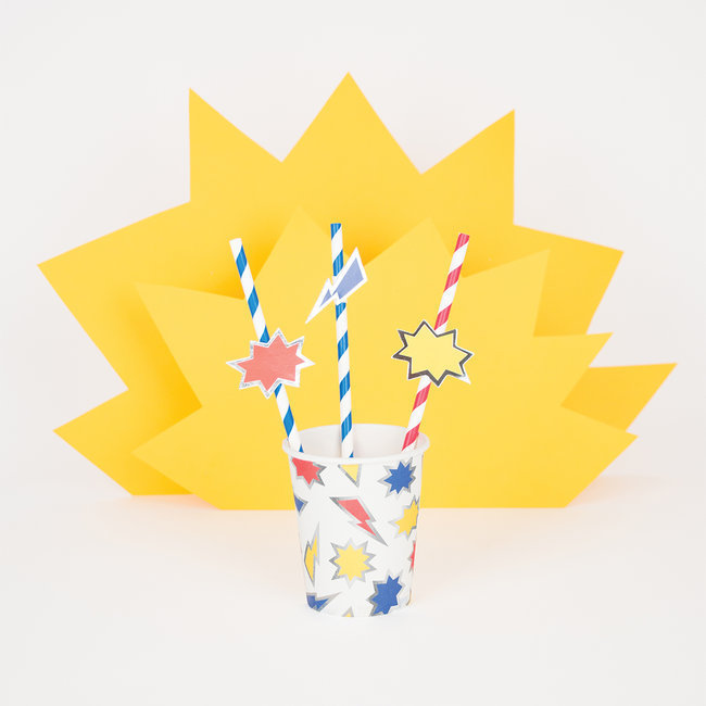 Copo com design de estrelas e raios e canudos coloridos com etiquetas, fundo amarelo