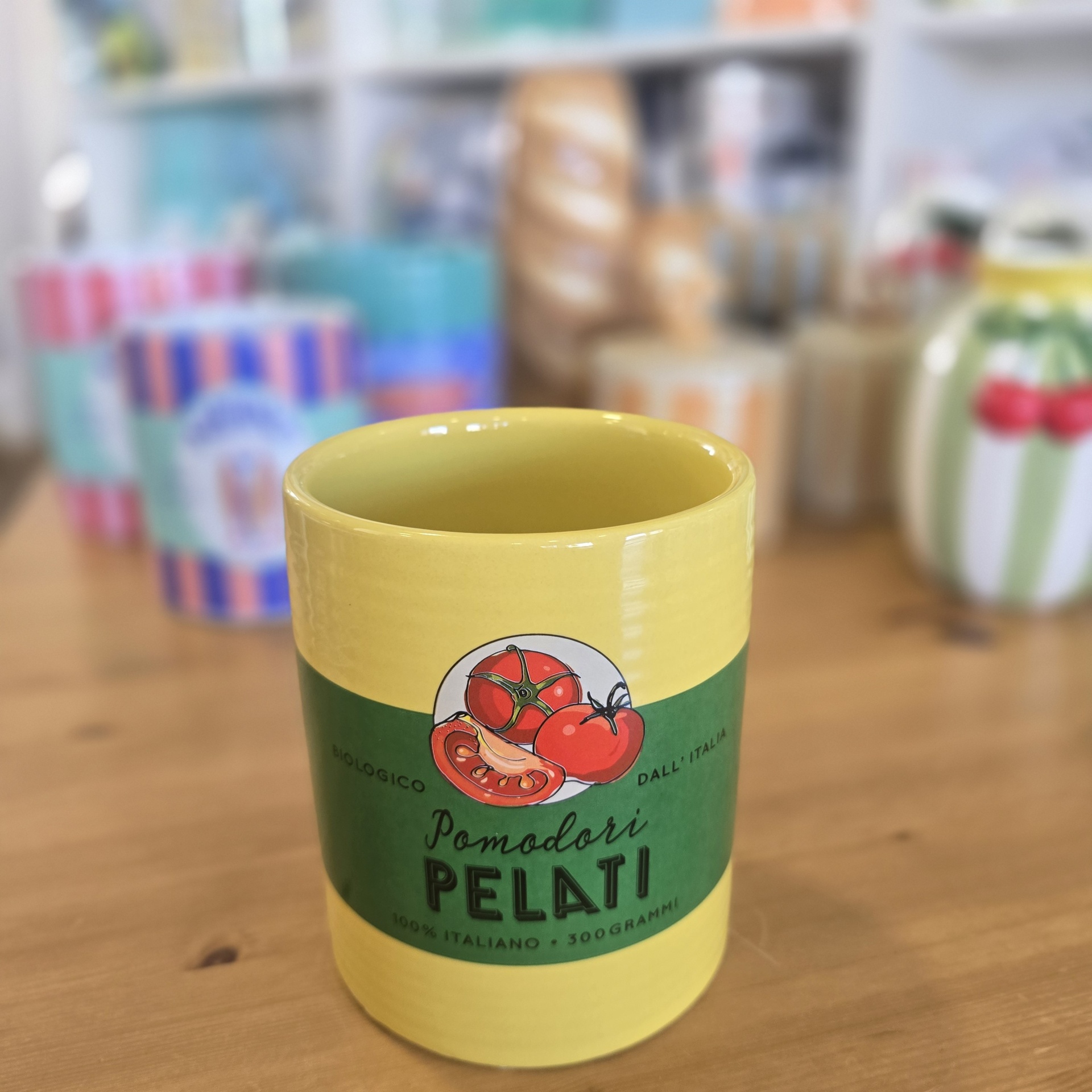Copo amarelo em cerâmica com etiqueta verde e desenho de tomates