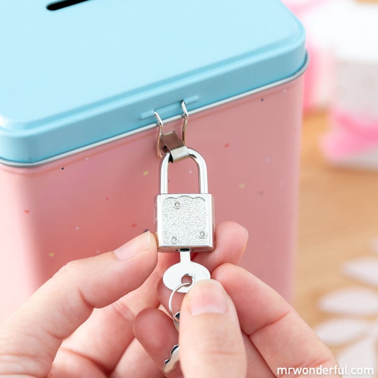 Caixa metálica azul e rosa com cadeado prateado a ser aberto por chave