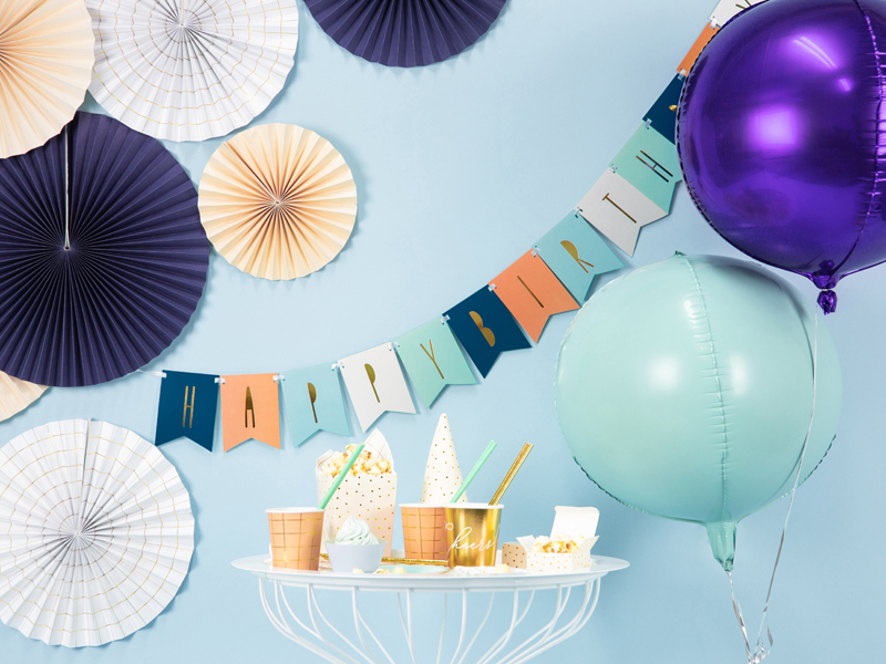 decoração de festa com leques de papel, balões metálicos e faixa HAPPY BIRTHDAY
