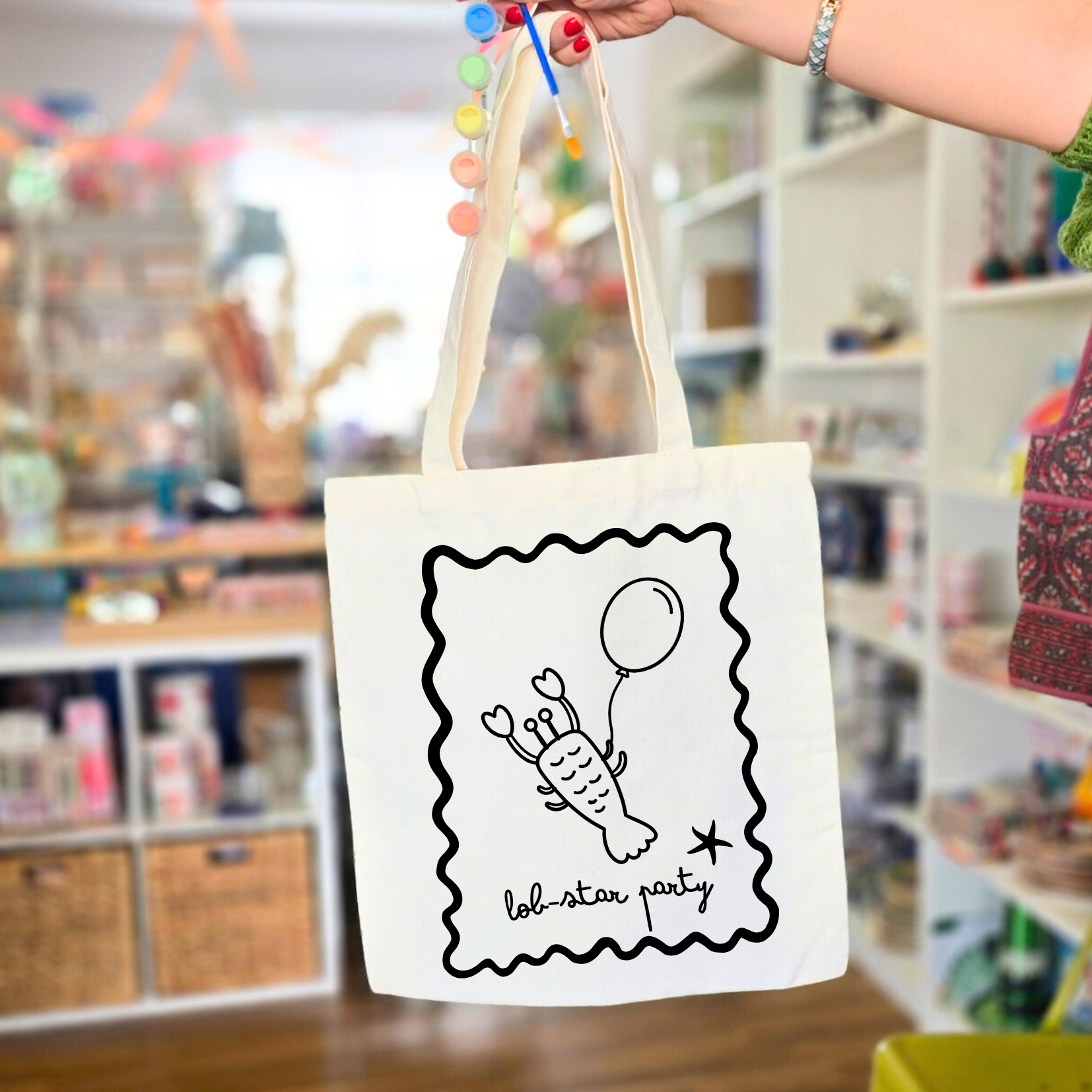 Saco reutilizável branco com desenho de lagosta a segurar balão e texto lob-star party.