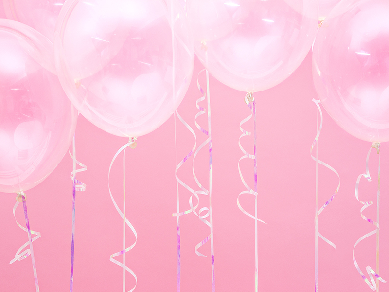 Oito balões de látex cor-de-rosa translúcido com fitas espiraladas pendentes, contra fundo cor-de-rosa.
