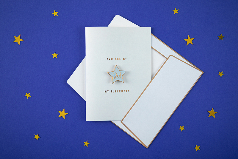 Conjunto de cartão de felicitações branco com texto dourado e estrela prateada sobre fundo azul com estrelas amarelas.