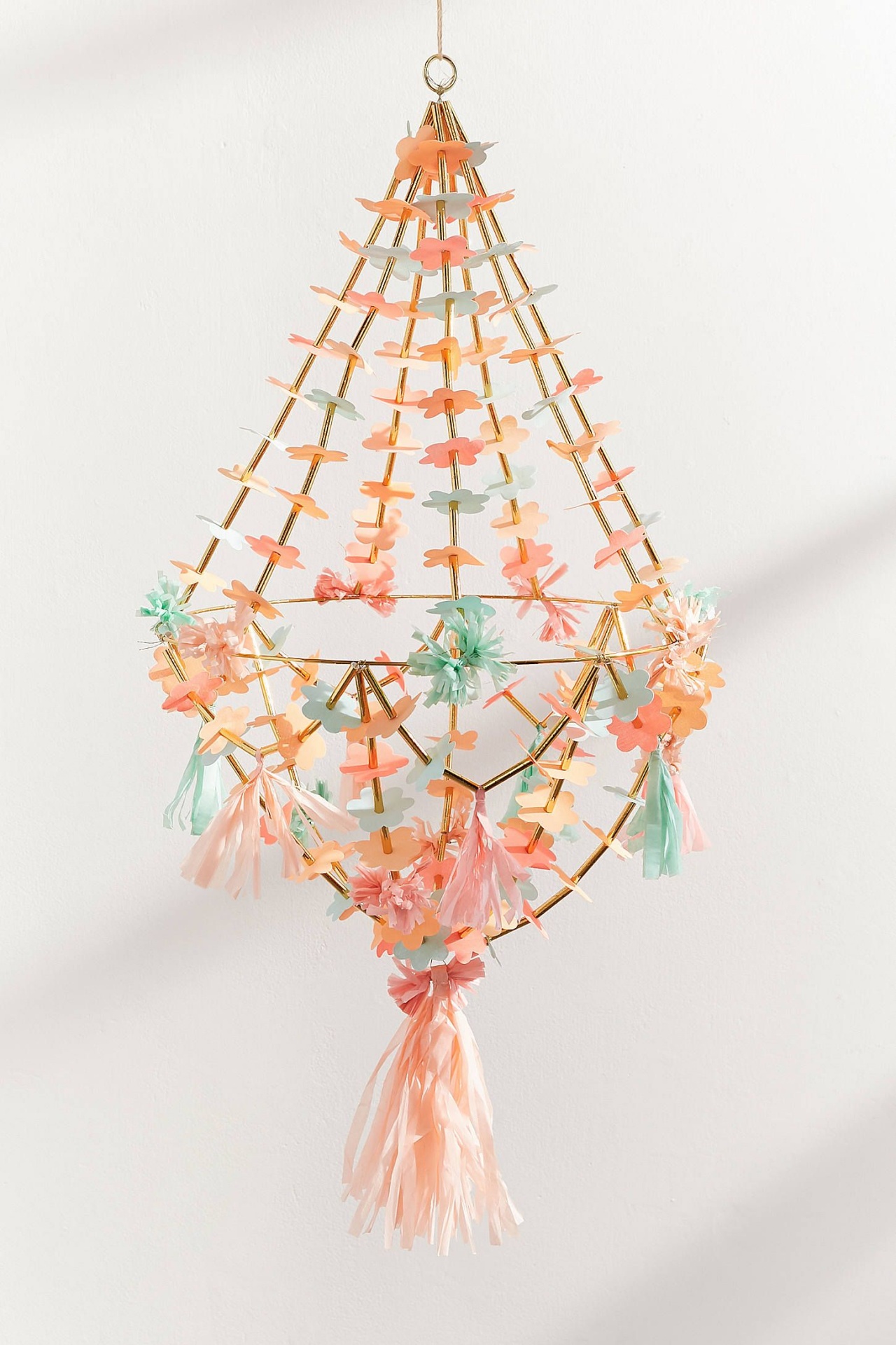 Móbile decorativo pendurado com flores em tons pastel e franjas, estrutura dourada