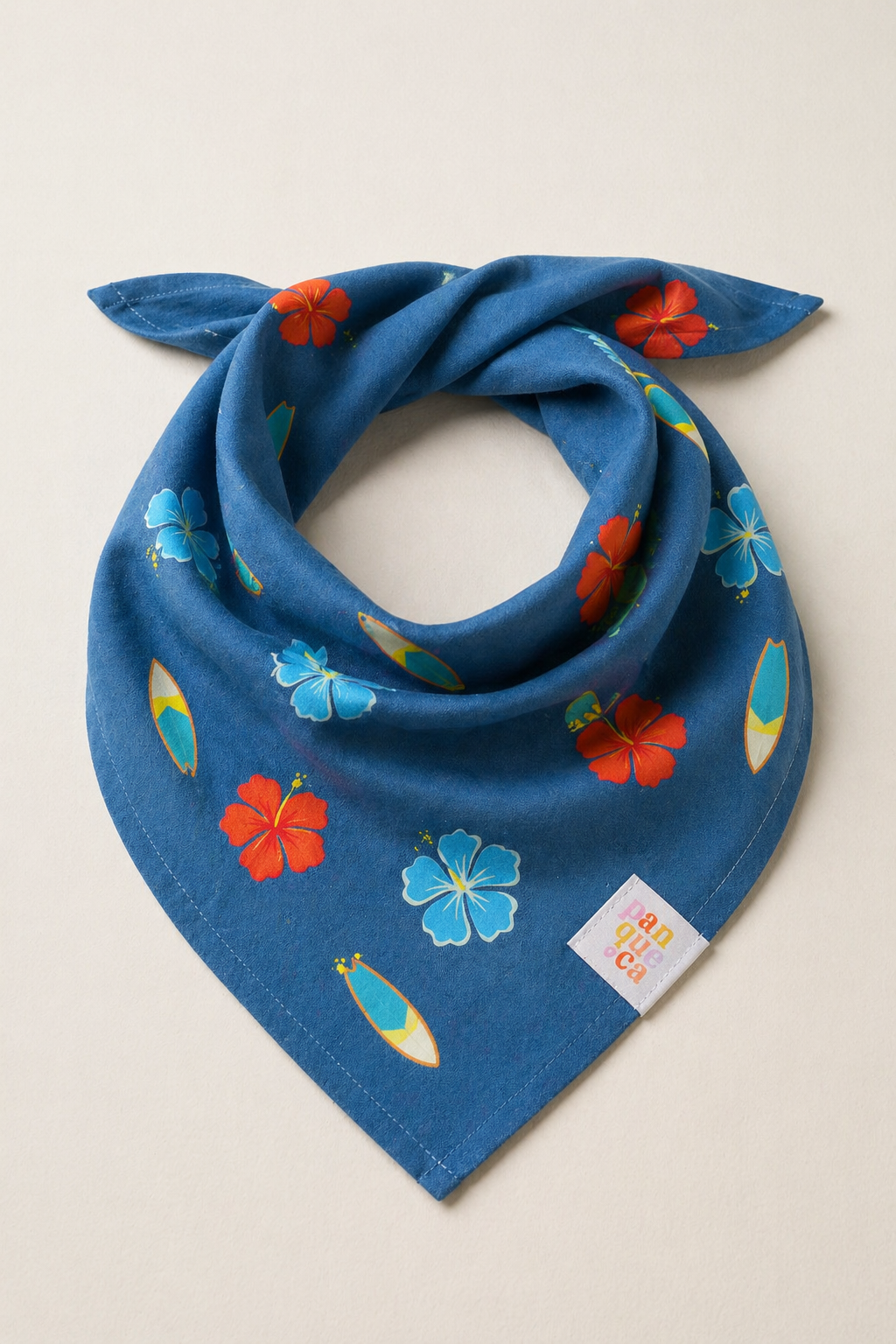 Bandana azul com flores vermelhas e azuis e pranchas de surf, com etiqueta branca que diz panqueoca