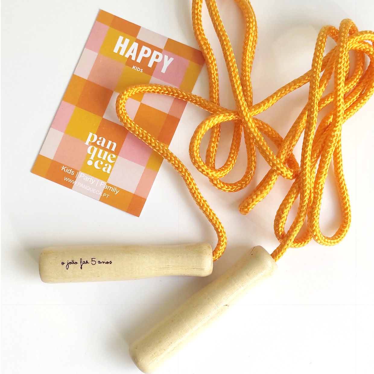 corda de saltar laranja com cabos de madeira clara e cartão xadrez com texto