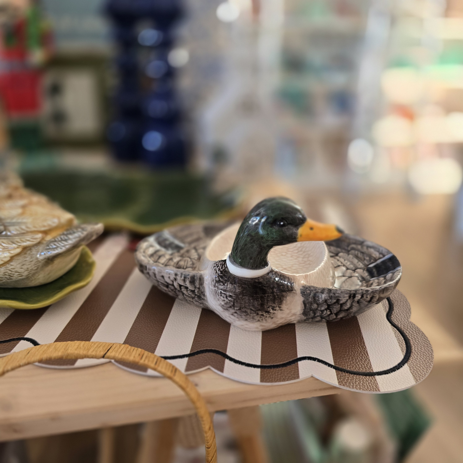 Vaso em cerâmica em forma de pato sobre toalha de mesa listrada castanha e branca