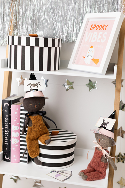 Prateleira decorada para Halloween com caixas riscas preto e branco, bonecas feiticeiras, livros decorativos e quadro SPOOKY VIBES