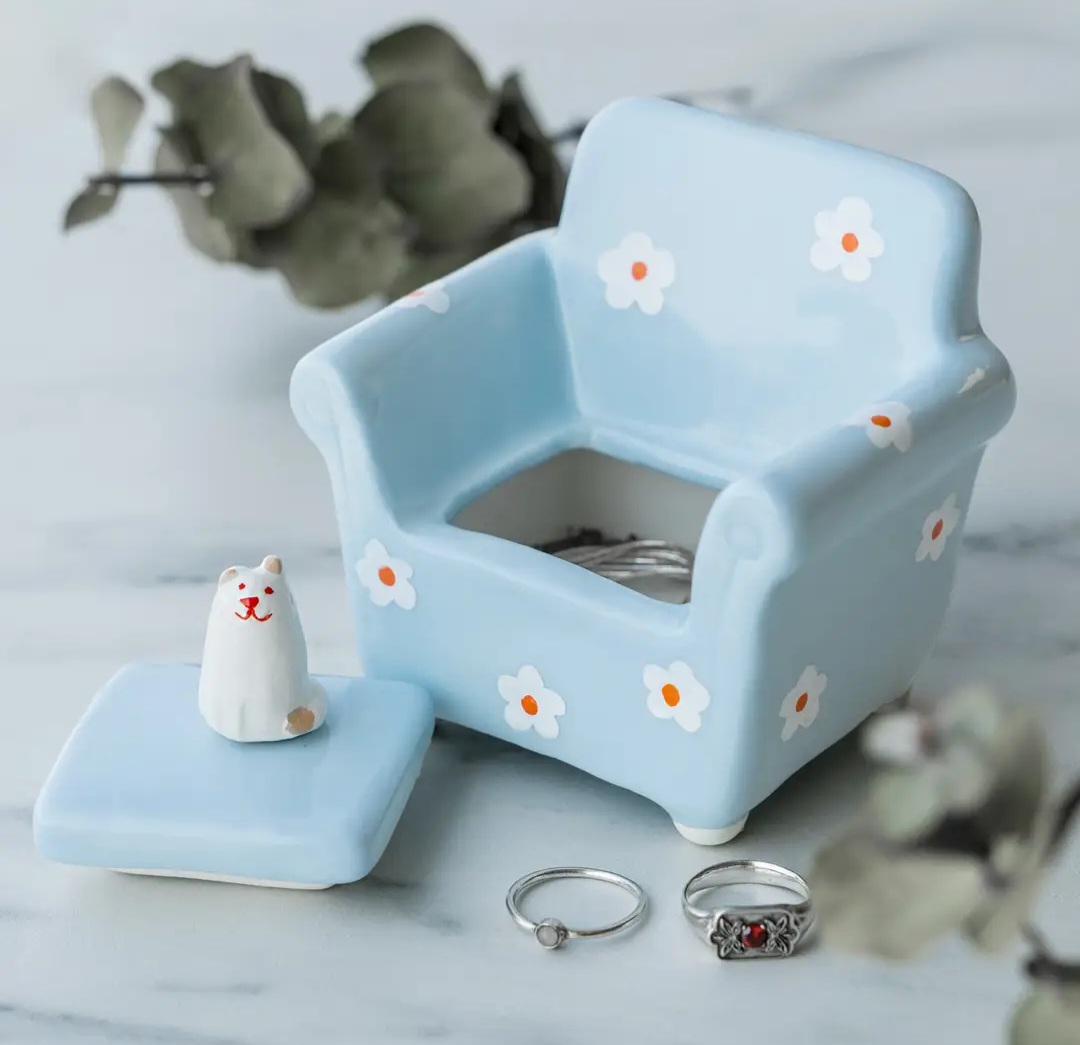 Caixa cerâmica azul clara em forma de poltrona com flores brancas e tampa com gato cerâmico branco