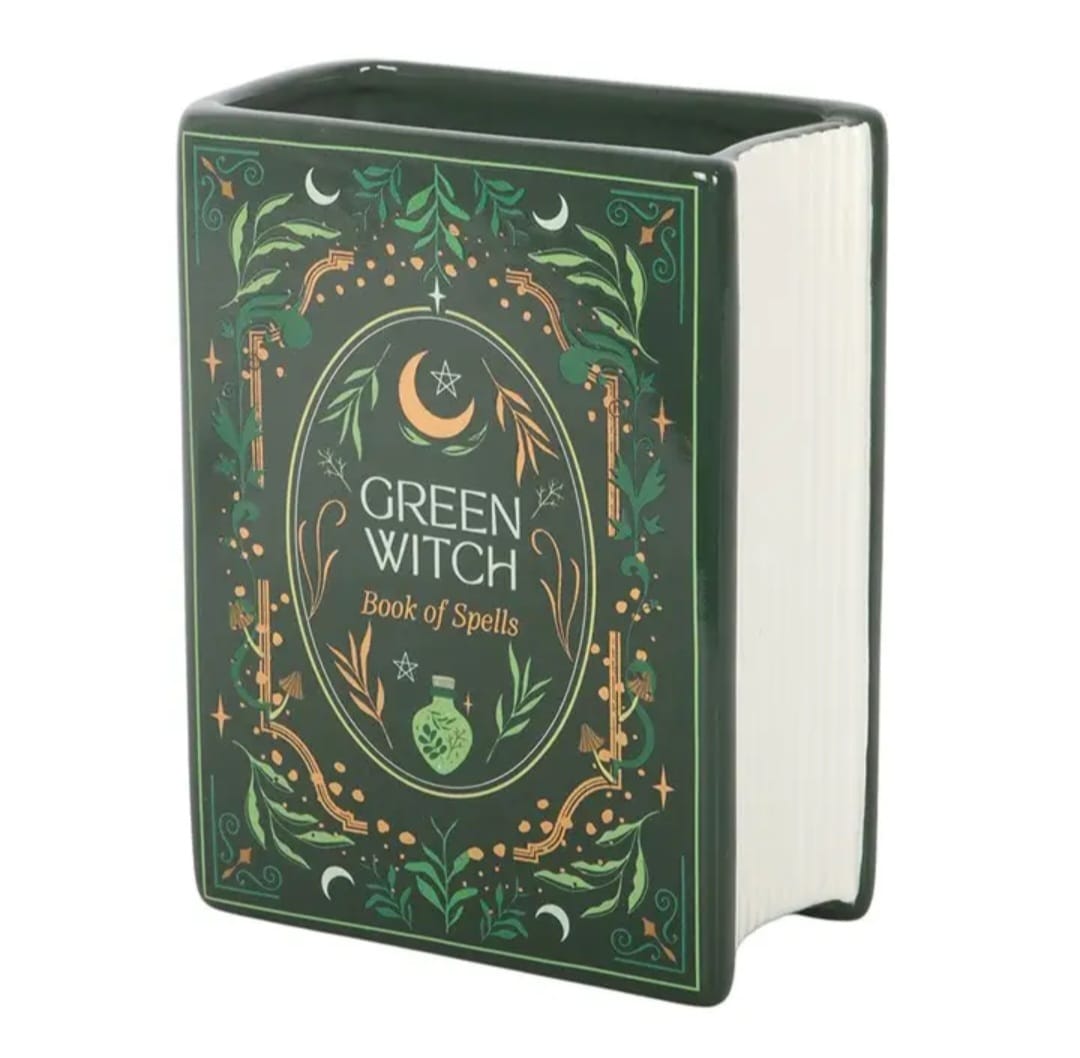 Livro em cerâmica verde com decoração de plantas e símbolo de lua