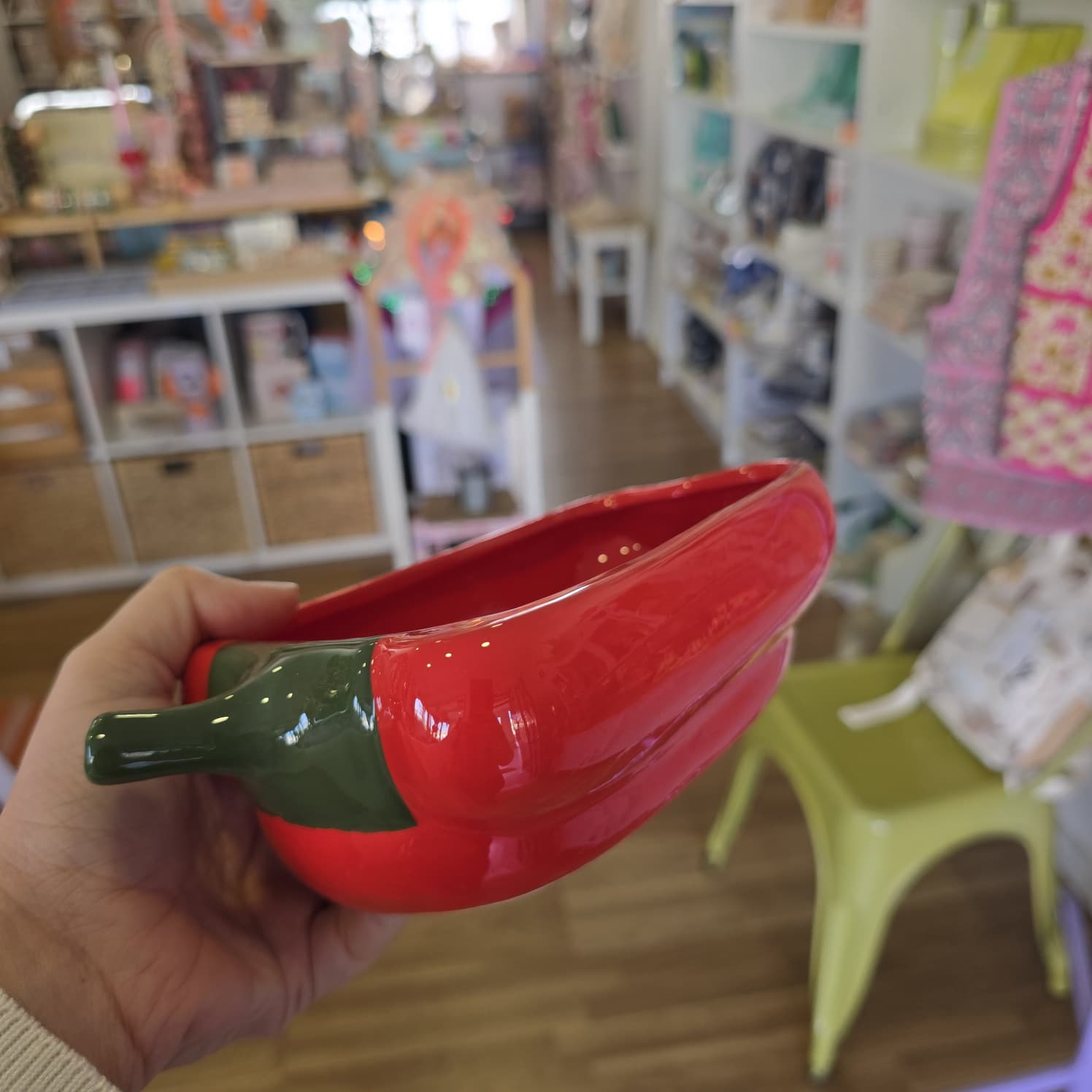 Tigela cerâmica vermelha em forma de malagueta com cabo verde numa loja