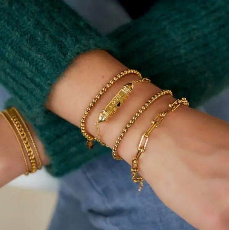 Pulseiras douradas femininas variadas no pulso