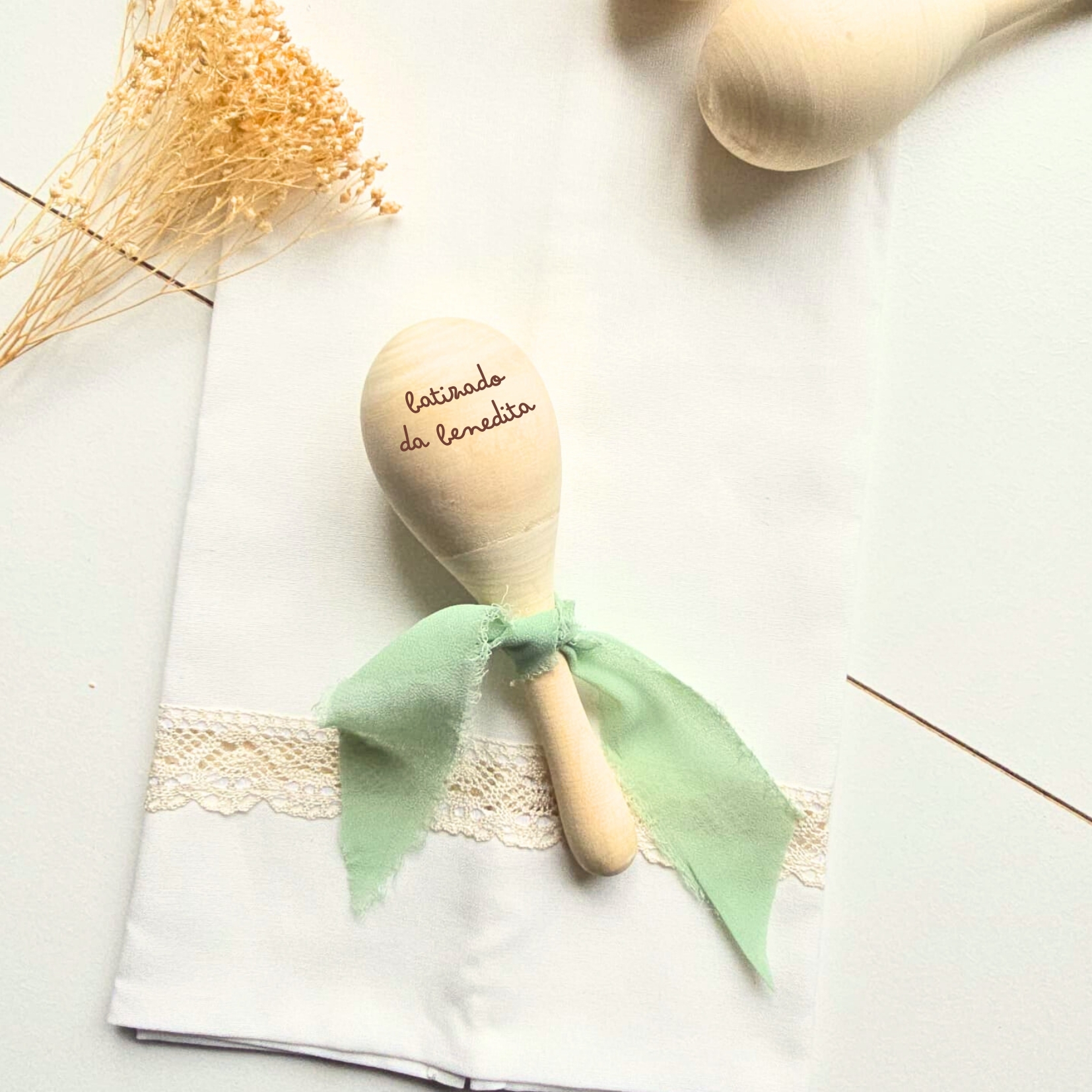 Colher musical de madeira com fita verde sobre pano branco com renda