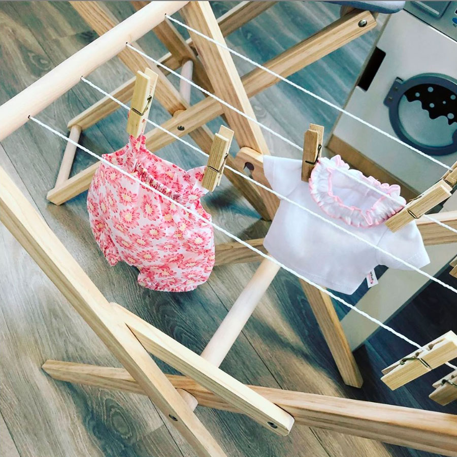 Roupas infantis penduradas em estendal de madeira